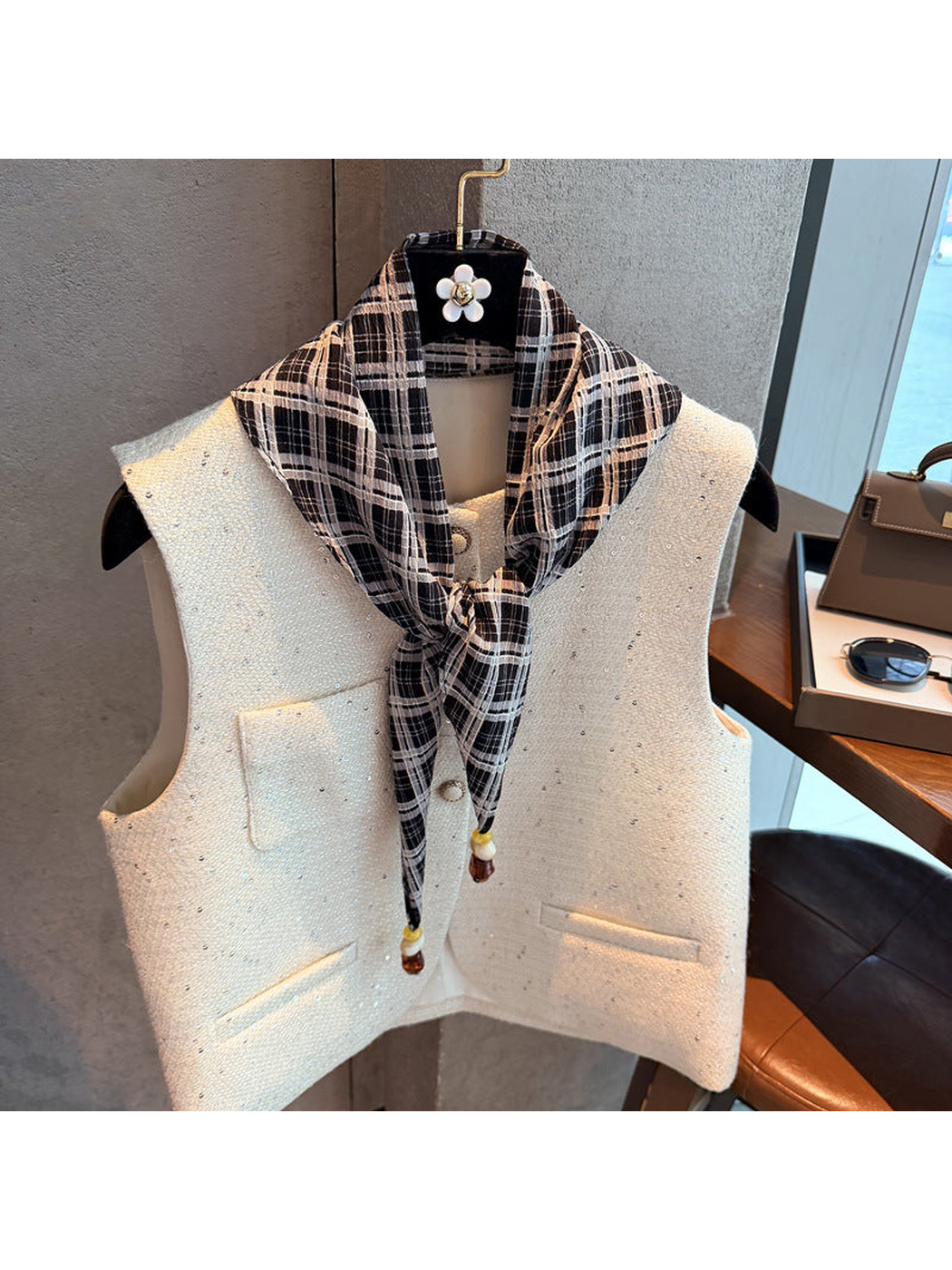 Black plaid scarf tied at the front over a white vest