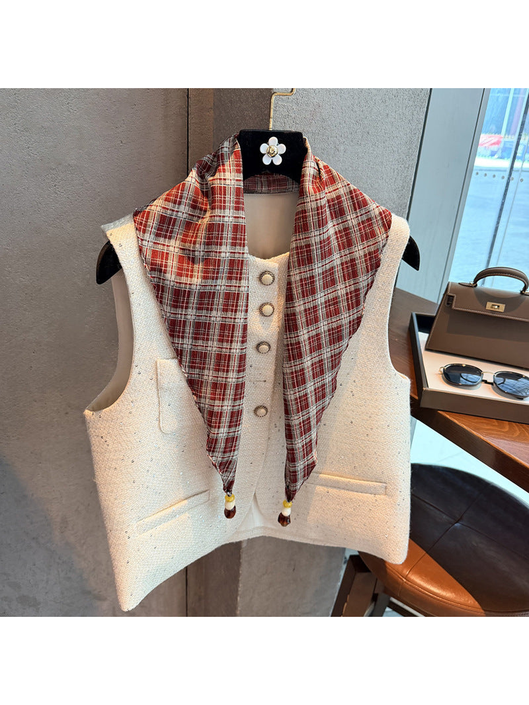 Red plaid scarf draped over a white vest with beaded pointed ends visible