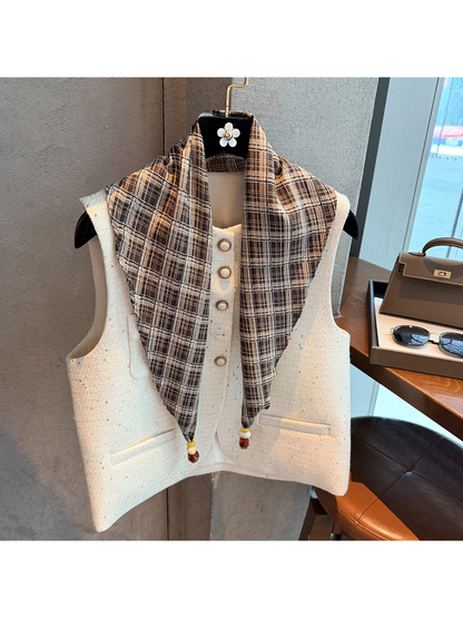 Khaki plaid scarf draped over a white vest with beaded pointed ends visible