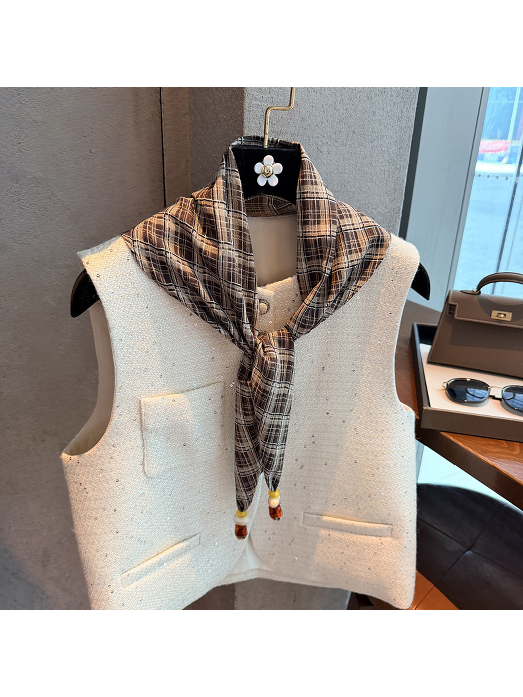 Khaki plaid scarf tied at the front over a white vest