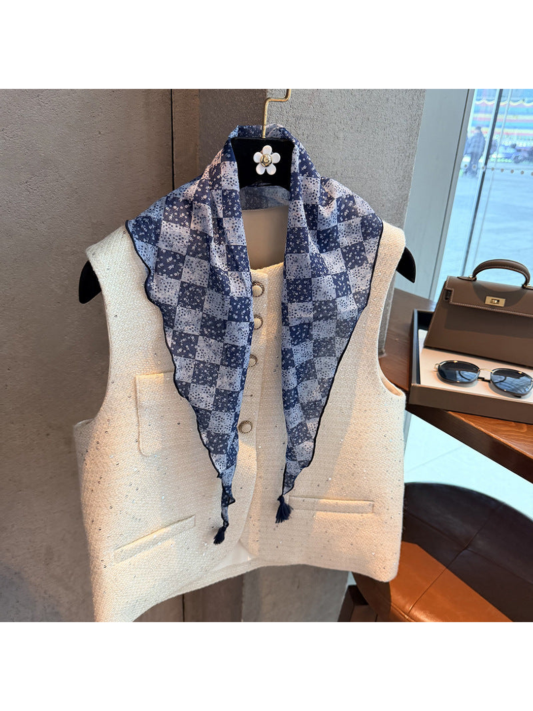 Navy checkerboard floral triangle scarf draped loosely over a vest