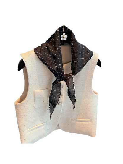 Black polka-dot triangle scarf tied around a white vest