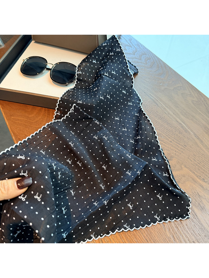 Close-up of the black scarf's semi-sheer crinkled surface and scalloped edge