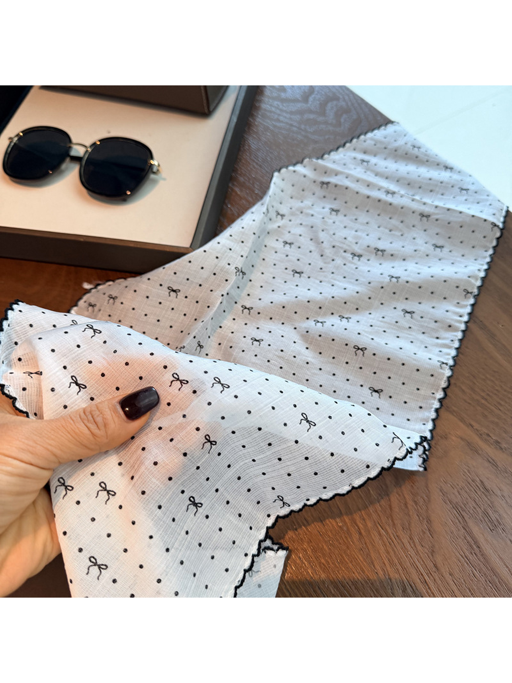Close-up of the white scarf's polka dots, small bow motifs and scalloped edging