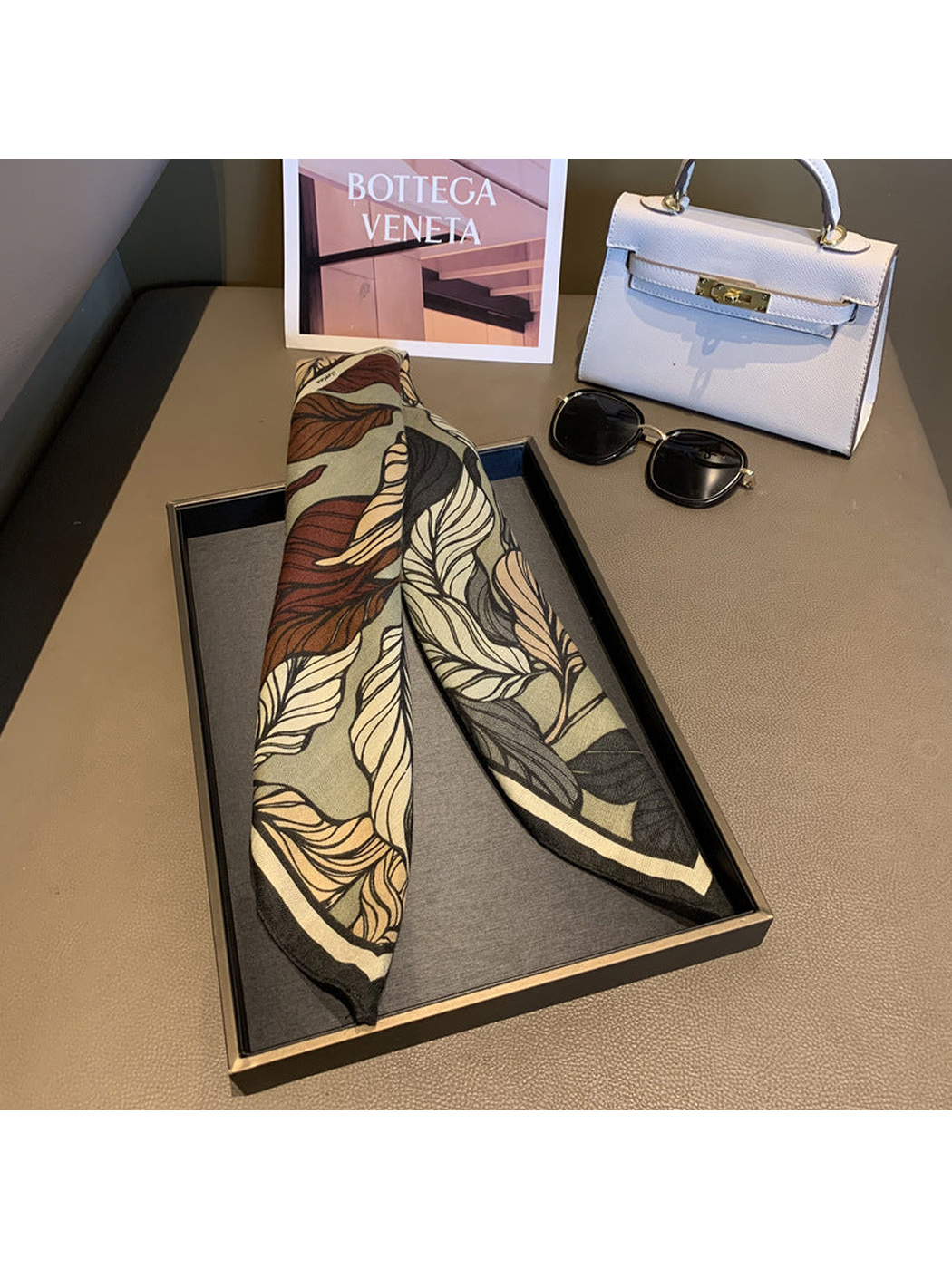 Army Green leaf-print scarf draped lengthwise on a display tray