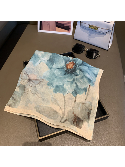 Blue-gray floral square scarf displayed folded on a tabletop