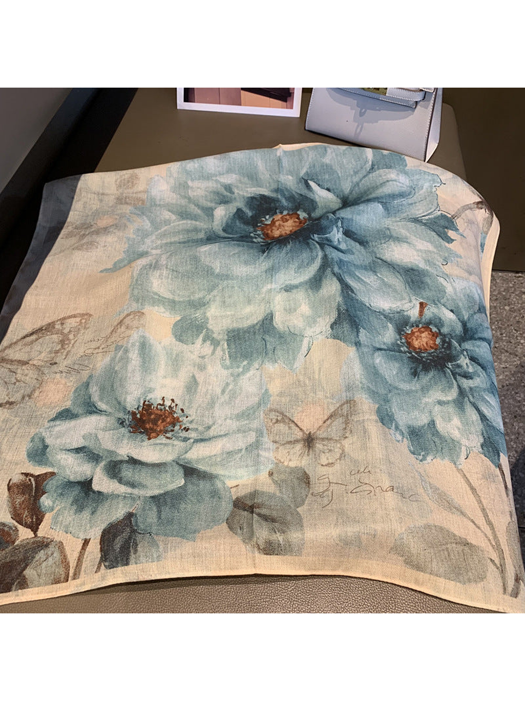 Close-up of oversized blue-gray flowers, butterflies and the narrow scarf border