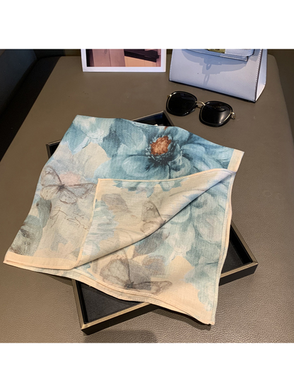 Blue-gray floral square scarf with one corner folded to reveal the paler reverse side