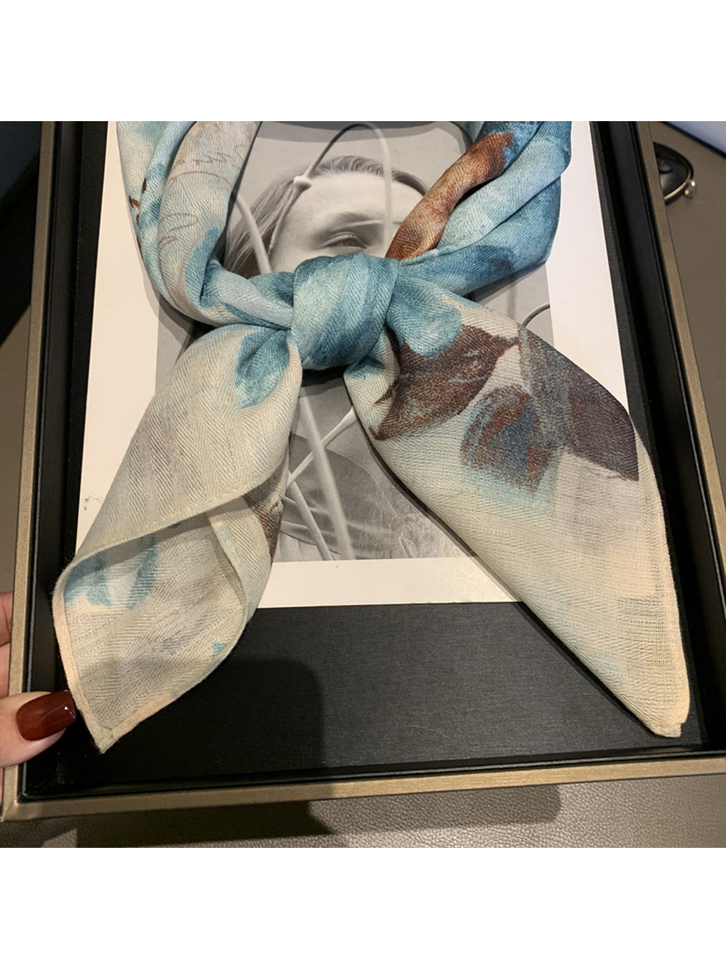 Close view of the blue-gray floral scarf tied in a knot with both ends visible