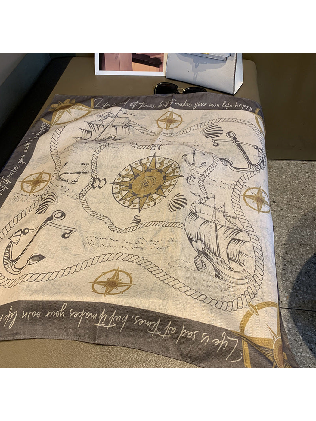 Cream and gray square scarf laid flat with ships, anchors, ropes and compass motifs
