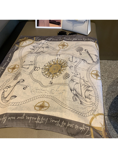 Cream and gray square scarf laid flat with ships, anchors, ropes and compass motifs