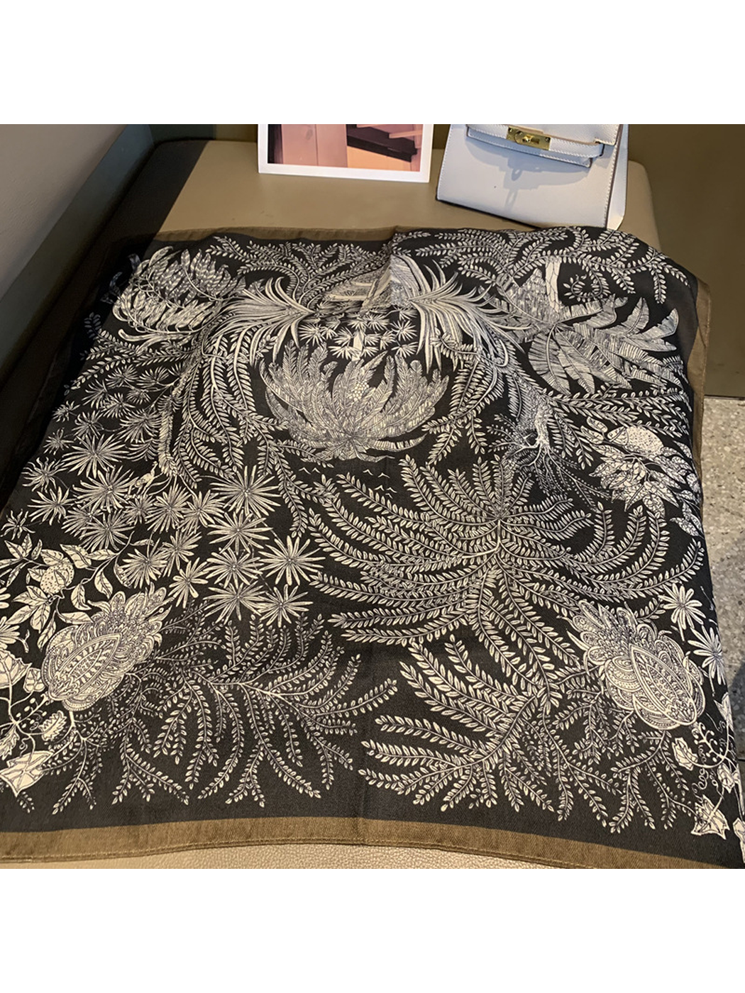 Black square scarf spread out with an intricate botanical print and contrasting border