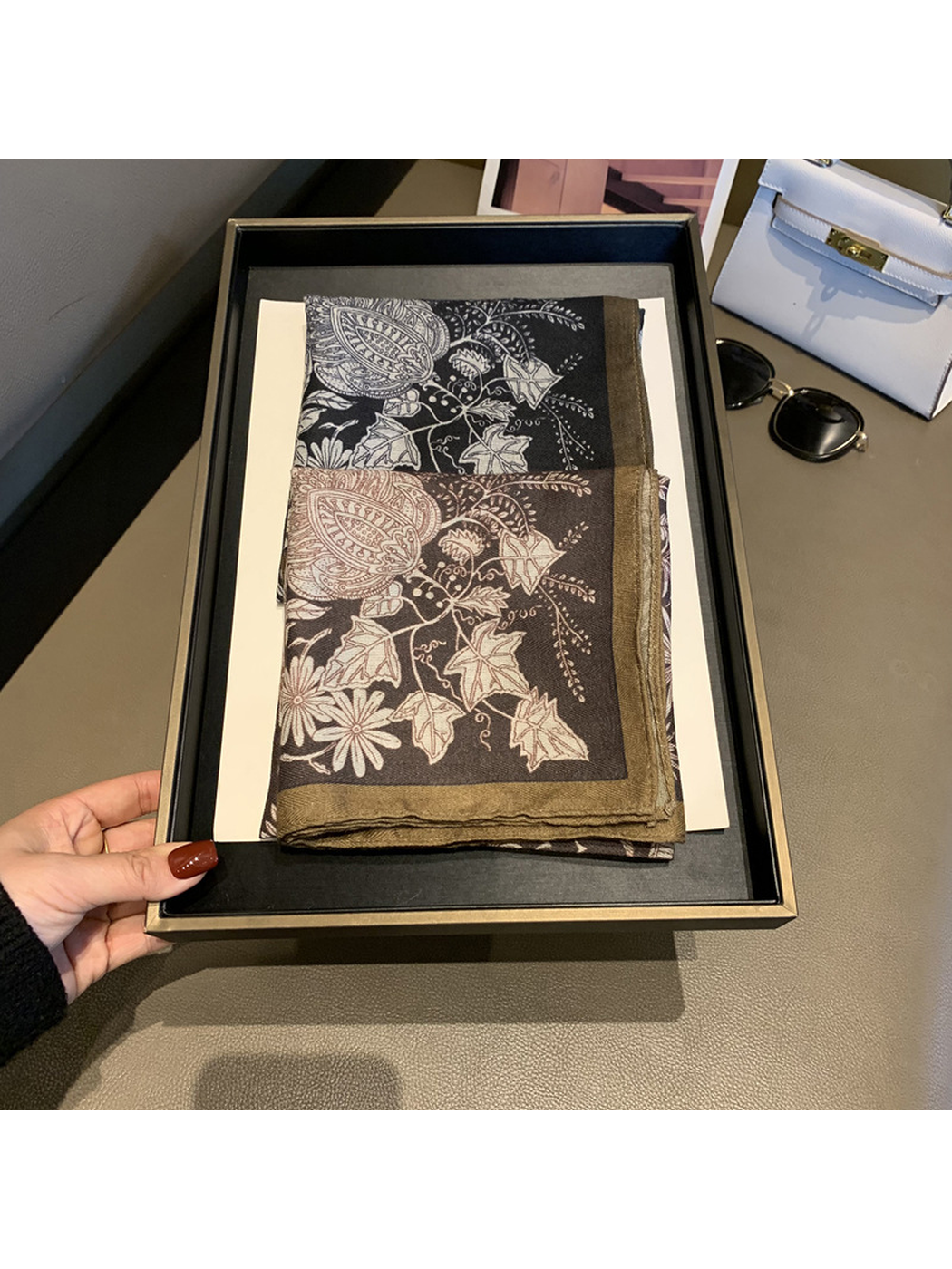 Black and Brown botanical square scarves folded together on a display tray