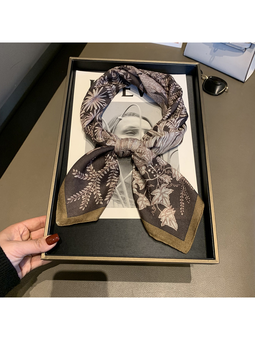 Brown botanical scarf styled in a knot on a display tray