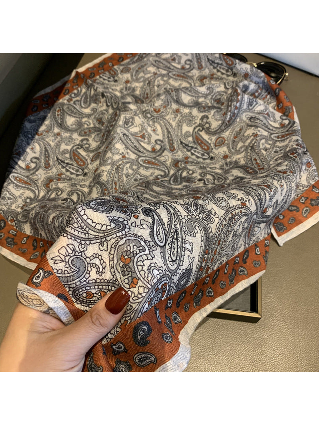 Close-up of the paisley pattern, woven-look texture and rust-orange border