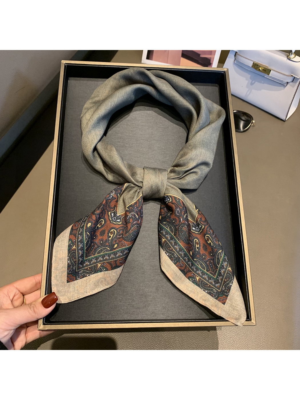 Gray square scarf tied to display its contrasting brown and green paisley ends