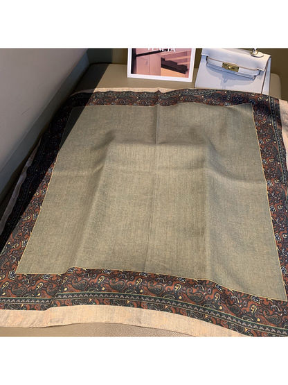 Square scarf laid open with a gray center and contrasting paisley border