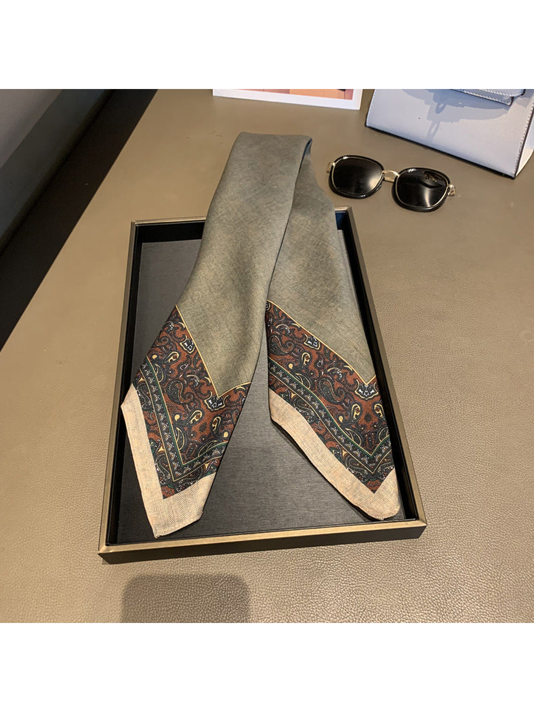 Gray scarf folded lengthwise with paisley-patterned ends