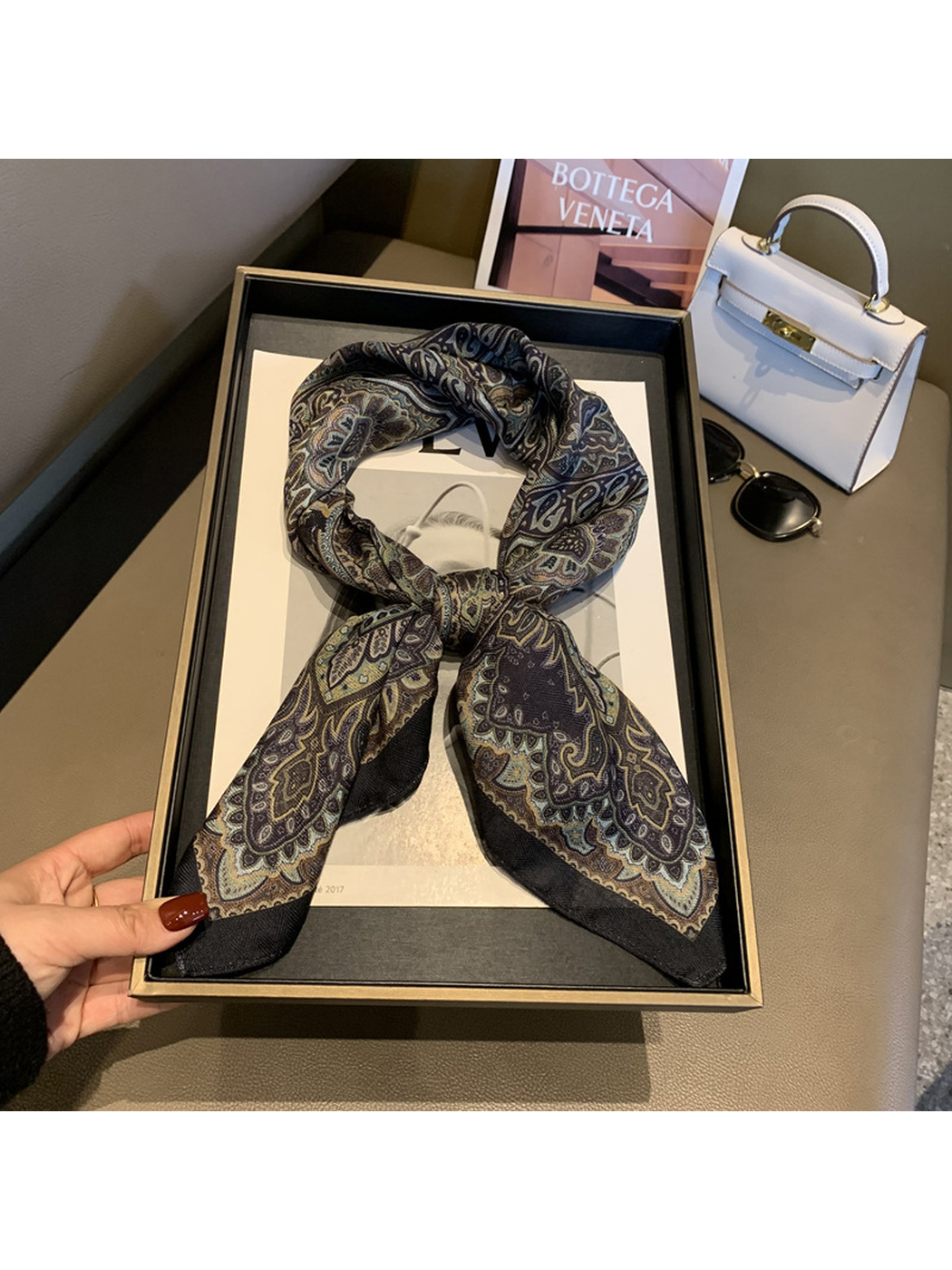 Dark paisley square scarf arranged in a tied loop with pointed ends