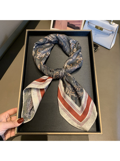 Dark gray paisley square scarf tied to show its rust-red striped border
