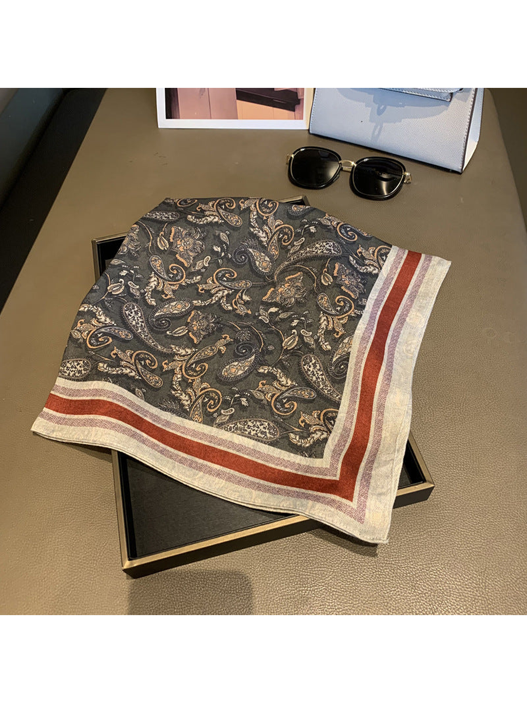 Dark gray paisley square scarf folded to display the contrasting striped border