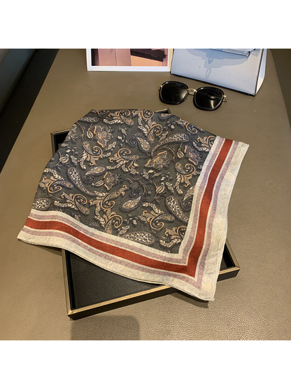 Dark gray paisley square scarf folded to display the contrasting striped border