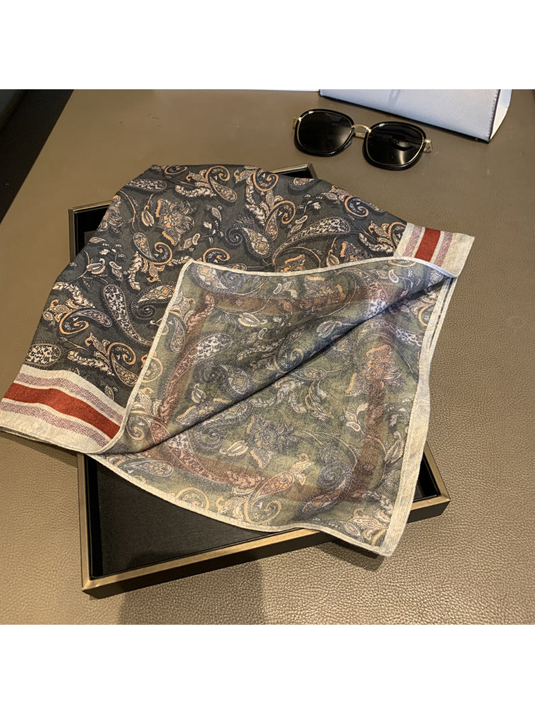 Folded corner showing the lighter reverse of the dark gray paisley scarf