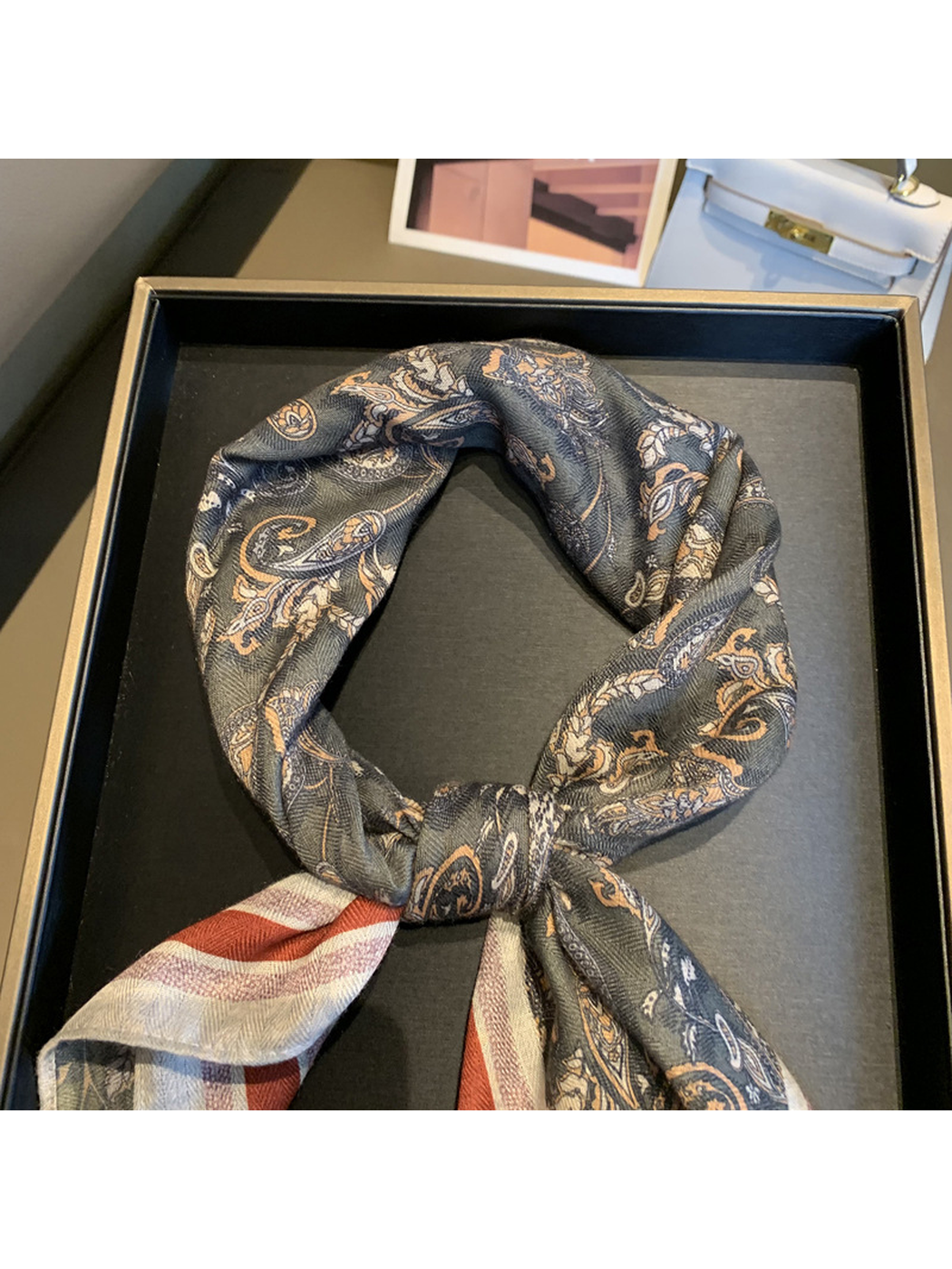 Close-up of the dark gray paisley pattern arranged in a scarf knot