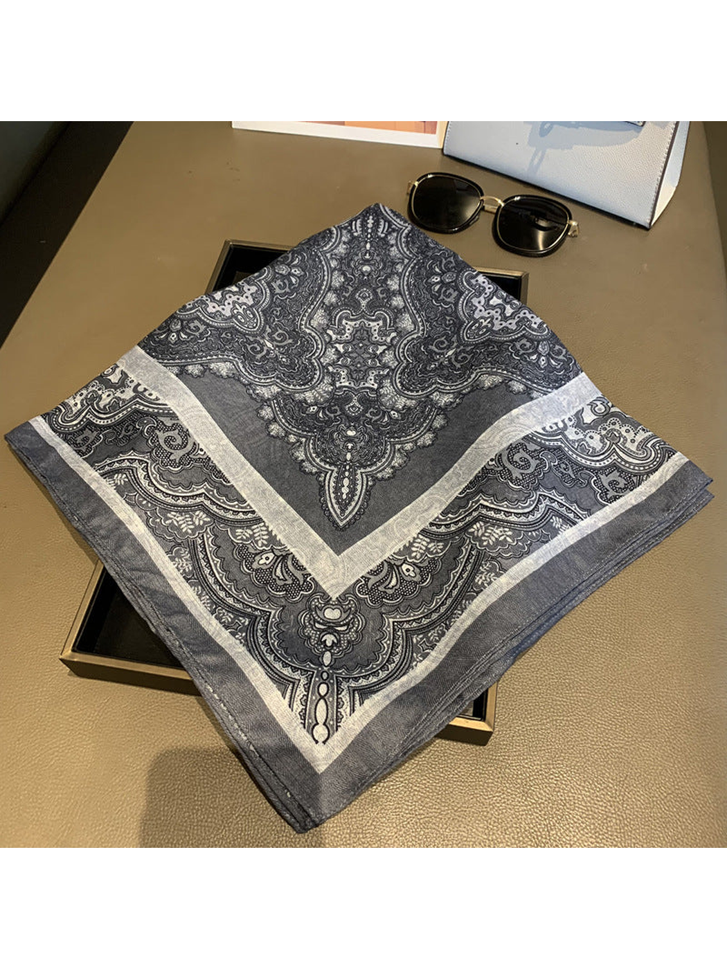 Gray-blue paisley square scarf folded to show its ornamental border
