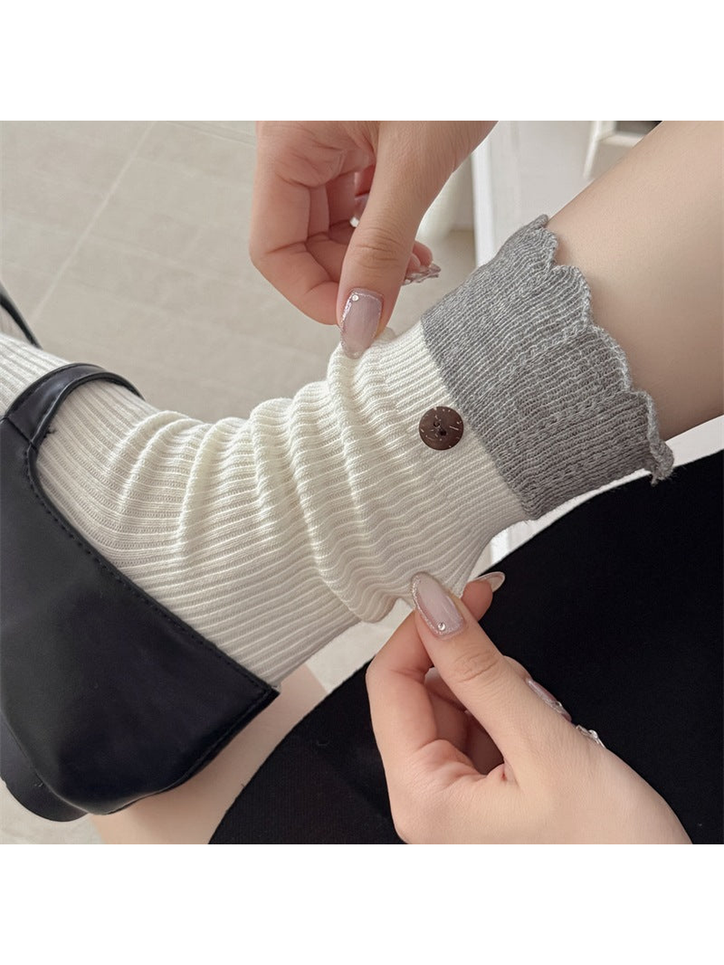 White ribbed crew sock with gray ruffled cuff and button accent, worn view