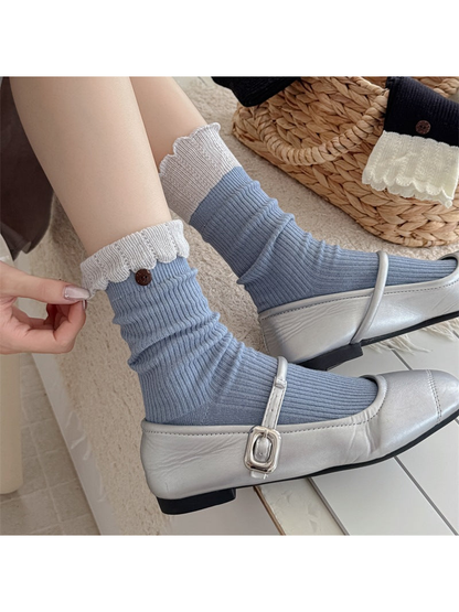 Blue ribbed crew socks with light gray ruffled cuffs and button accents, worn view