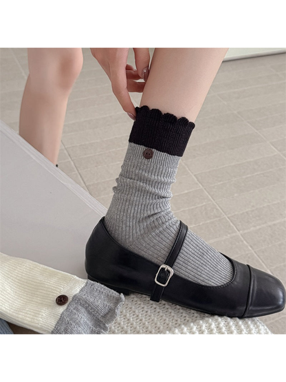 Light Gray ribbed crew sock with black ruffled cuff and button accent, worn view