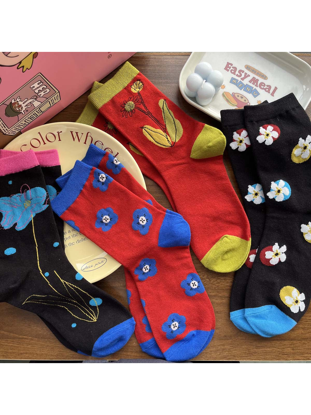 Four floral crew sock styles arranged across decorative plates