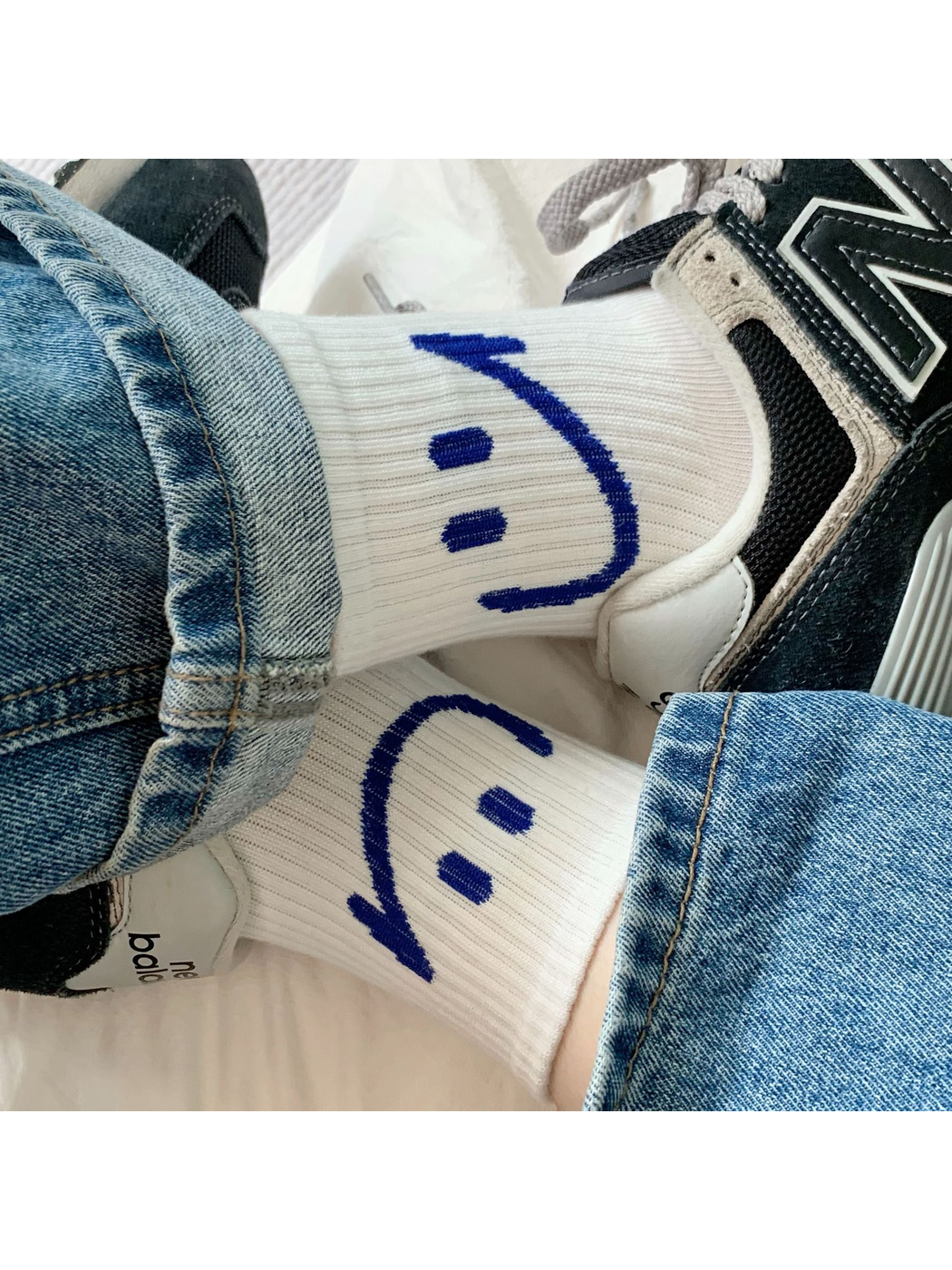White smiley crew socks worn with jeans and black-and-white sneakers