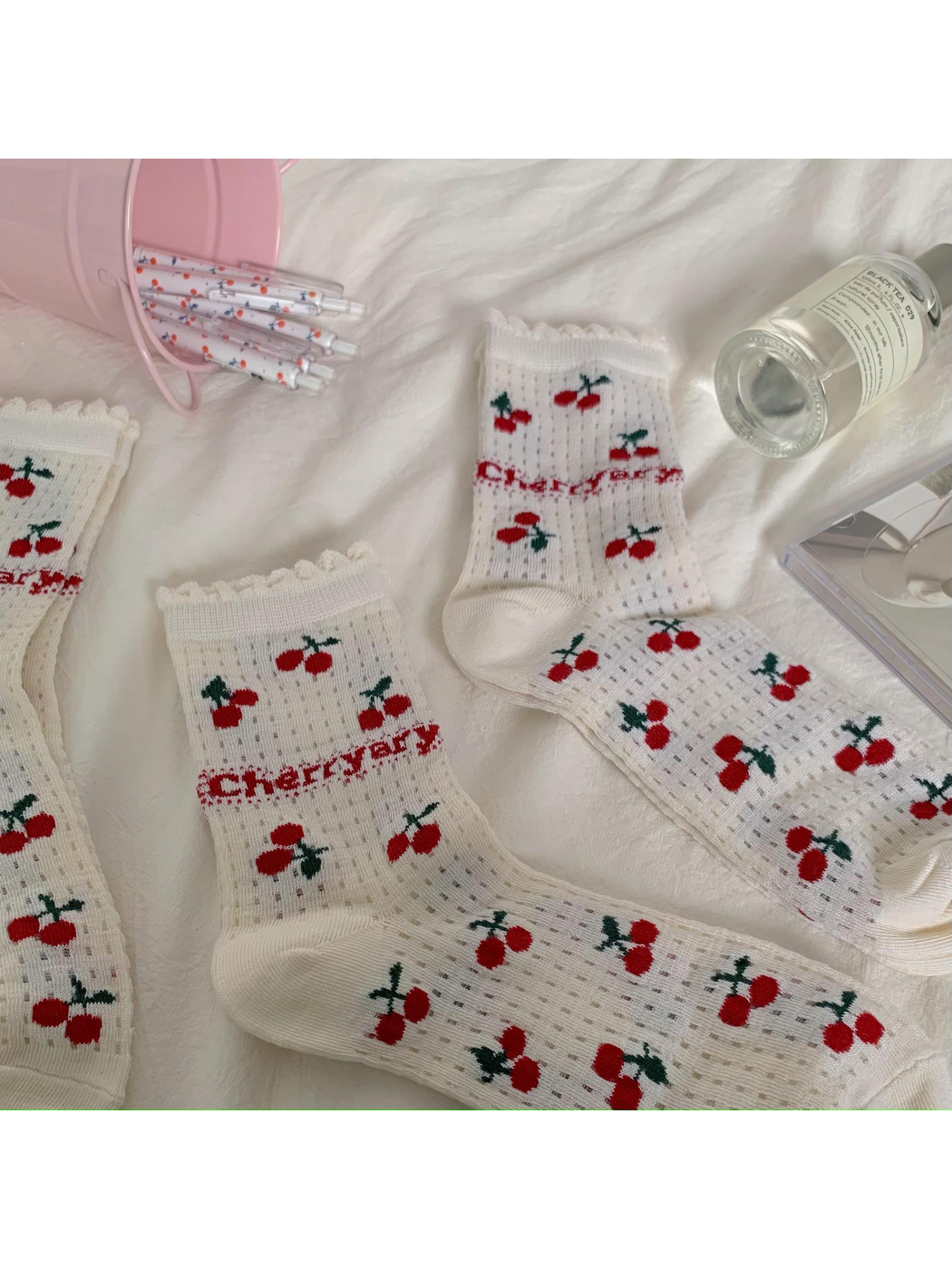 Ivory cherry-pattern socks arranged on a light fabric background