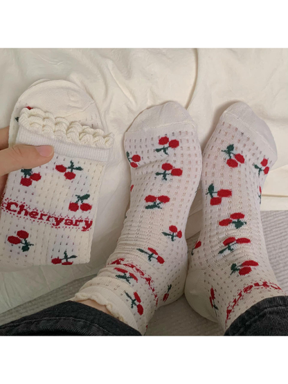 Ivory cherry-pattern crew socks worn with the ruffled cuffs visible