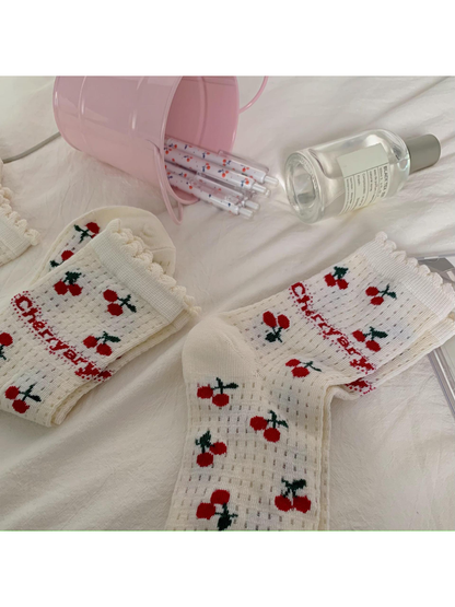 Ivory cherry-pattern socks showing openwork knit rows and ruffled cuffs