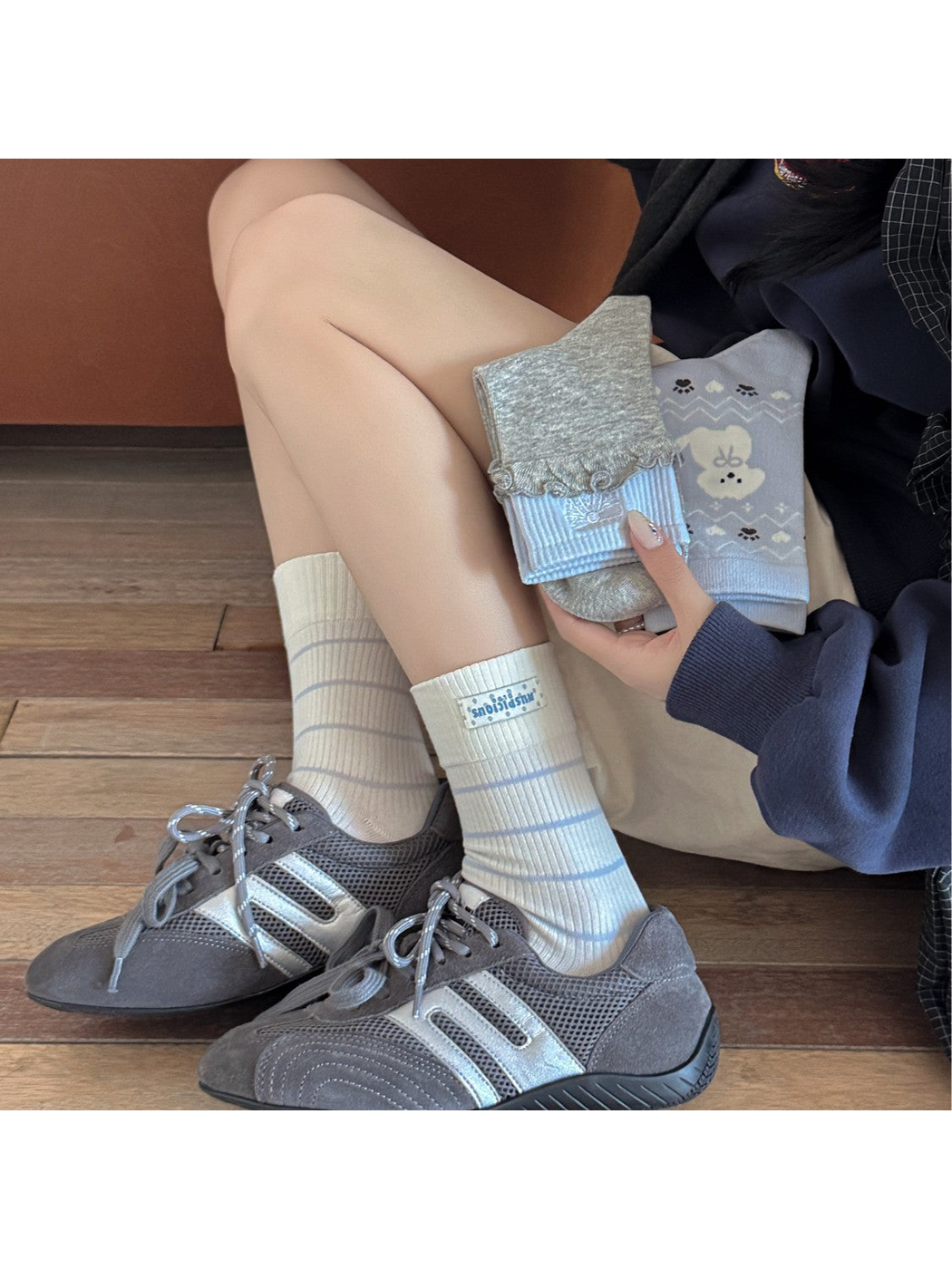 Ivory striped crew socks worn with gray sneakers beside folded light blue and gray styles