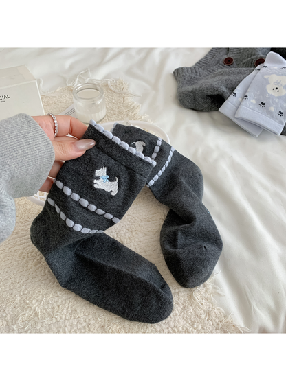 Close-up of dark gray crew socks with an embroidered white dog and raised light blue stripes