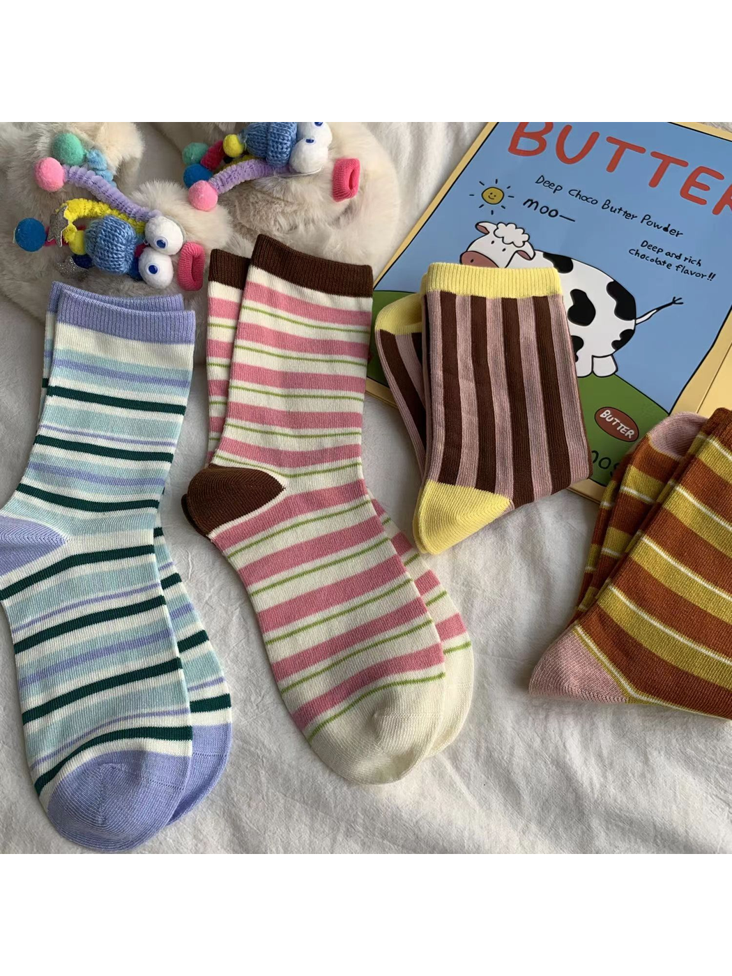 Four striped crew sock styles arranged with colorful decorative props