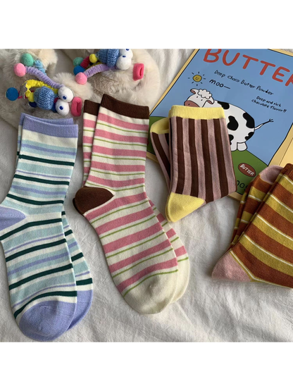 Four striped crew sock styles arranged with colorful decorative props