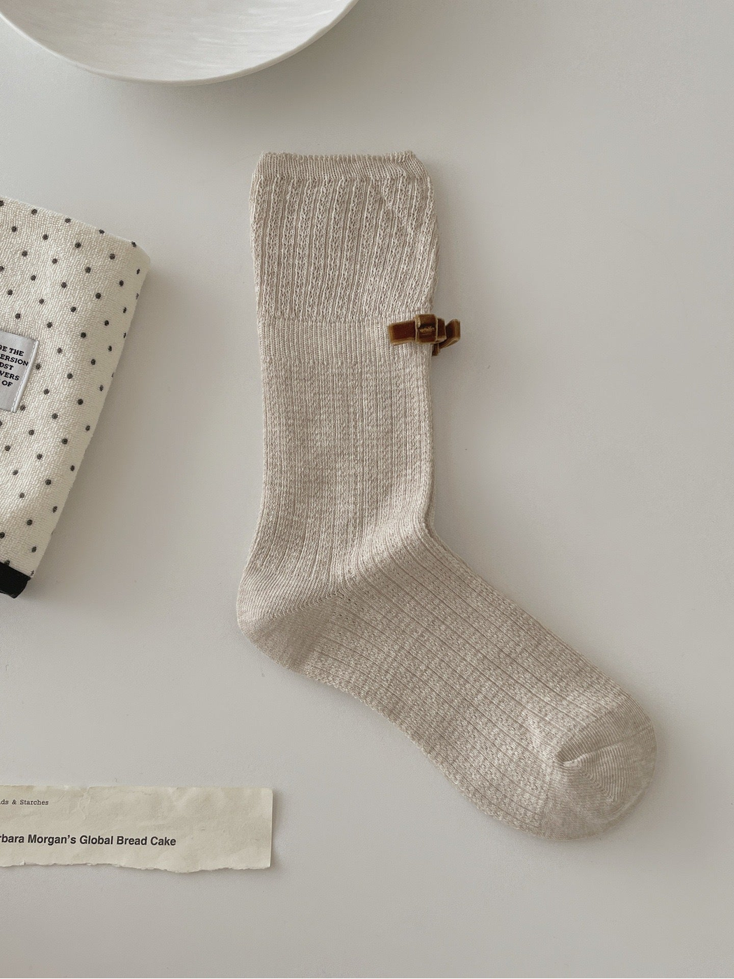 Beige ribbed crew sock with openwork cuff and brown bow accent
