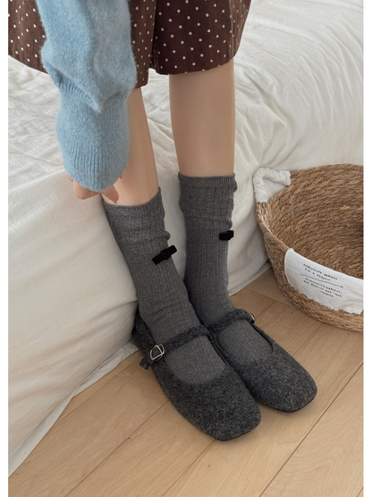 Gray ribbed bow socks worn with gray Mary Jane shoes