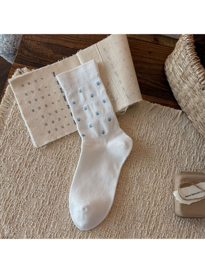 White crew sock with miniature blue flower motifs, flat display