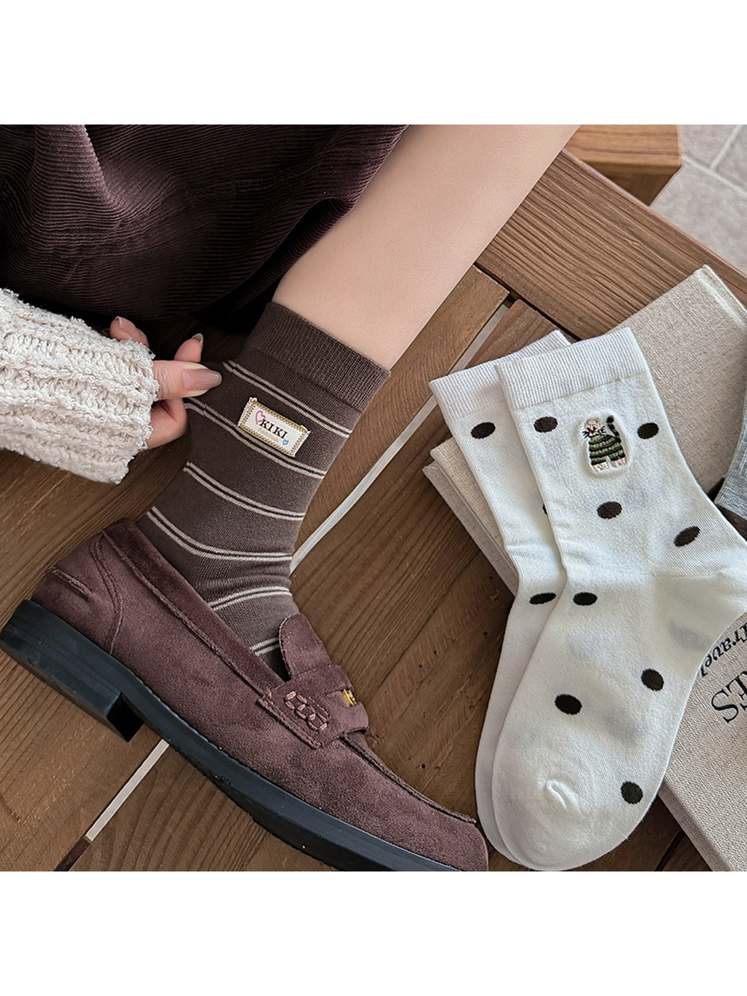 Striped brown crew socks worn with Polka Dot socks displayed beside them