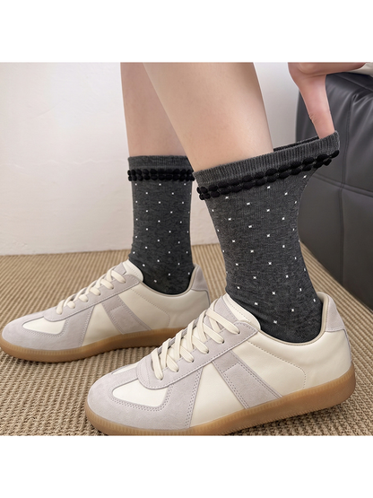 Dark gray polka-dot crew socks worn with low-top sneakers