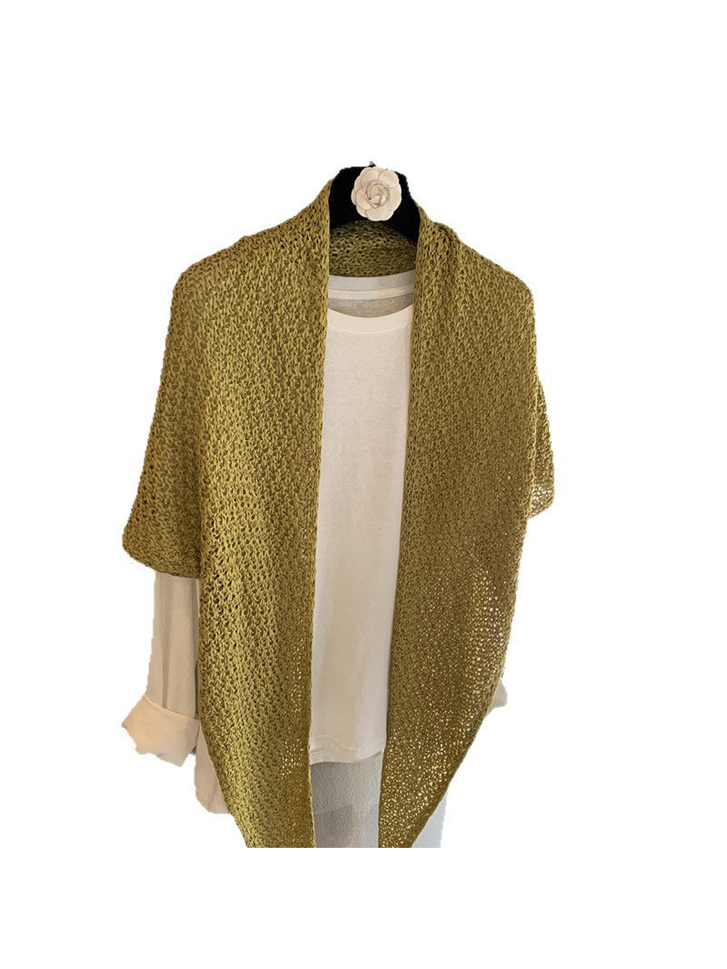 Green openwork triangle scarf draped over a white top on a hanger