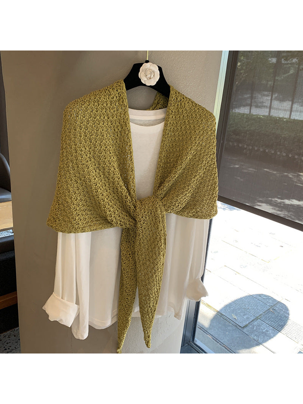 Green openwork triangle scarf tied over a white top