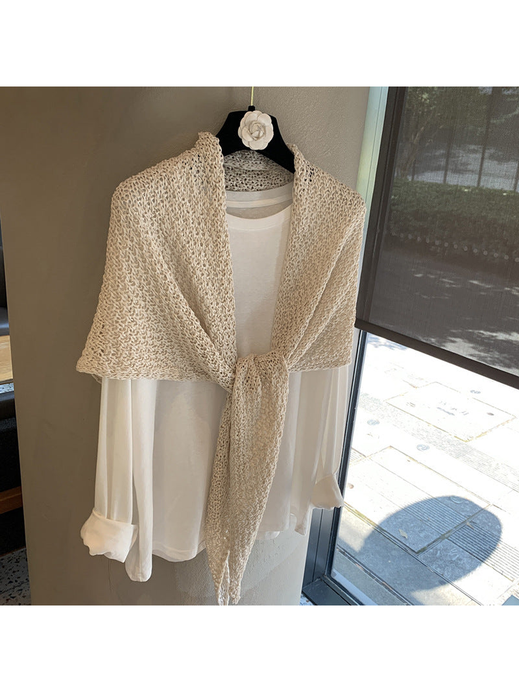 Beige openwork triangle scarf tied over a white top