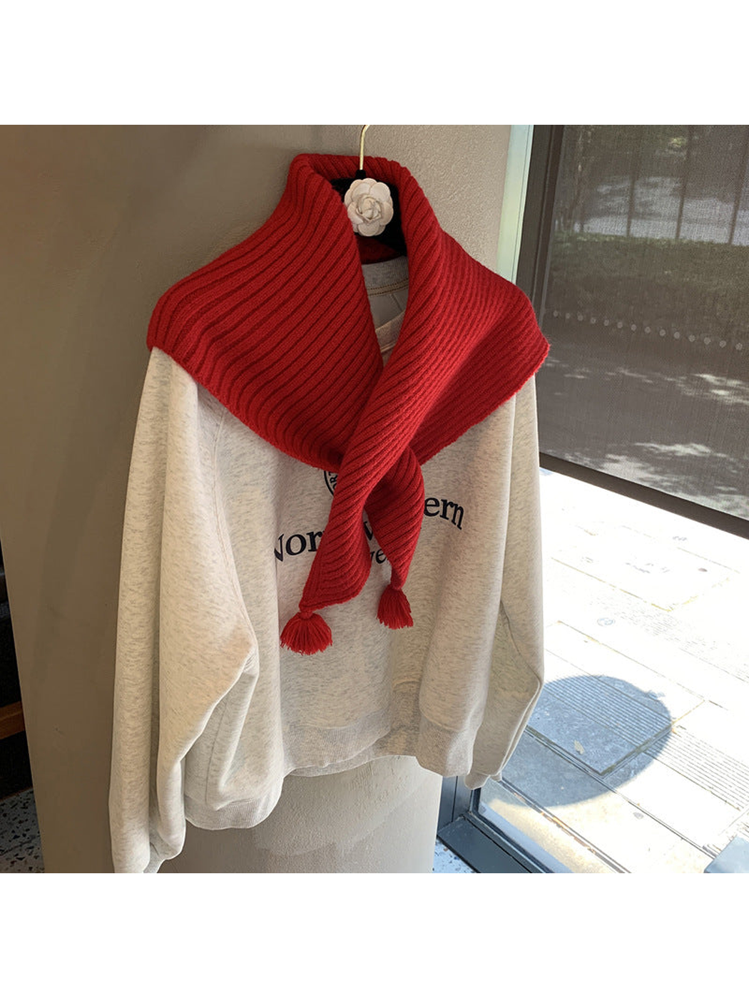 Red ribbed triangle scarf crossed at the front with tassel ends
